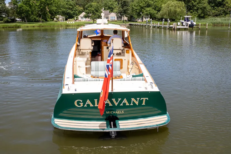 Slide: The Image of 1997 Hinckley Picnic Boat Classic on calm water, rear view with flag and lush surroundings. - 8