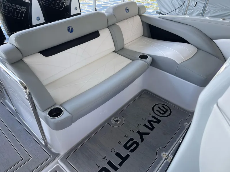 Slide: The Image of 2022 Mystic Powerboats M3800 interior with gray and white seating, cup holders, and branded flooring. - 14