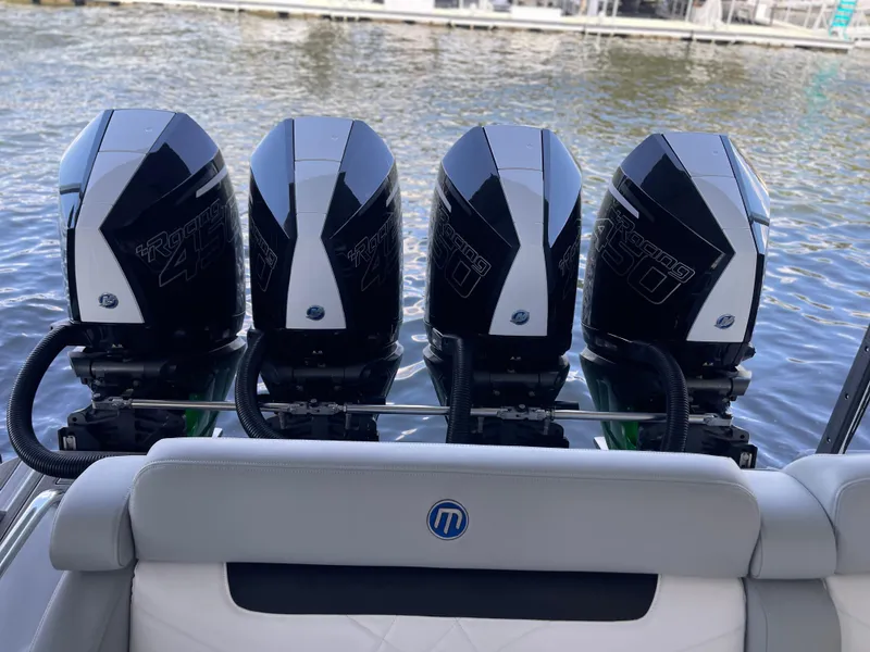 Slide: The Image of 2022 Mystic Powerboats M3800 with four powerful outboard motors on a calm water backdrop. - 15