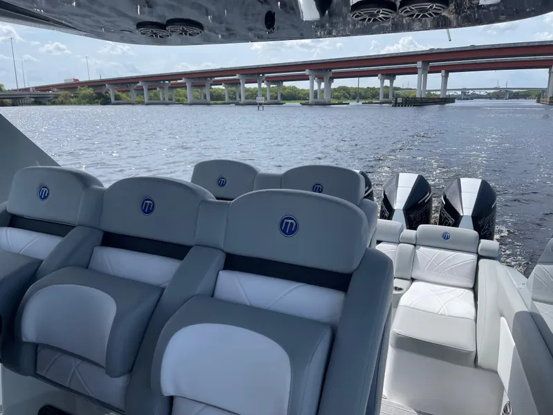 Slide: The Image of 2022 Mystic Powerboats M3800 interior with plush seating, overlooking a scenic waterway and bridge. - 3