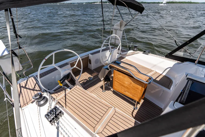 Slide: The Image of 2023 Hanse 348 sailboat cockpit with dual steering wheels and wooden deck on open water. - 16