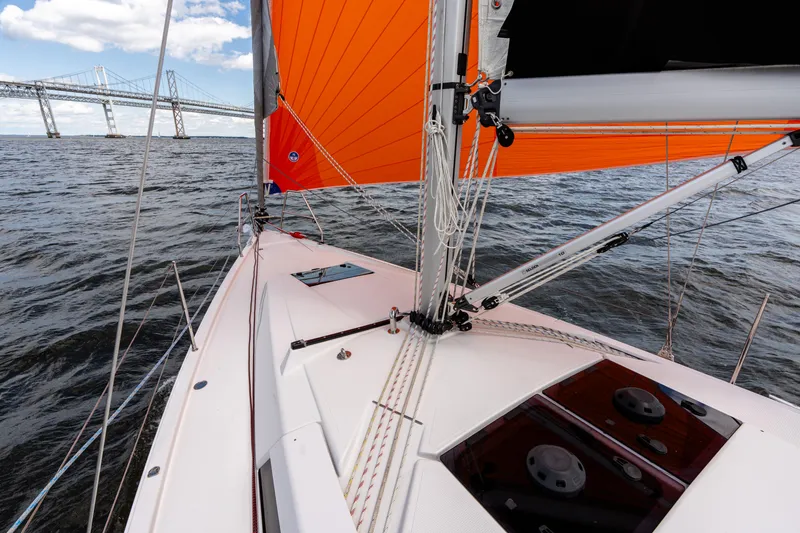 Slide: The Image of 2023 Hanse 348 sailboat with orange sails on open water near a bridge. - 18