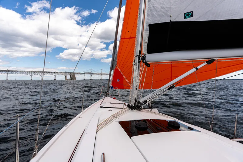 Slide: The Image of Sailing on a 2023 Hanse 348 yacht with vibrant orange sails near a bridge. - 19