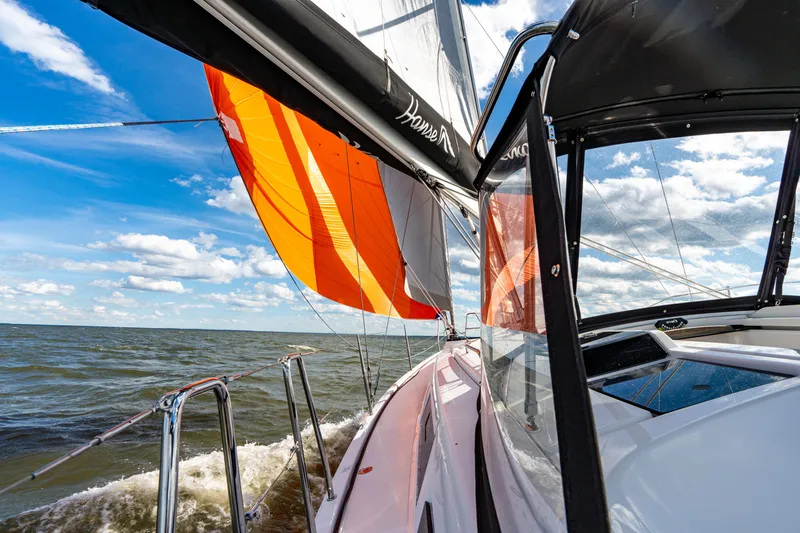 Slide: The Image of 2023 Hanse 348 sailboat with vibrant orange sail on open water under blue sky. - 21