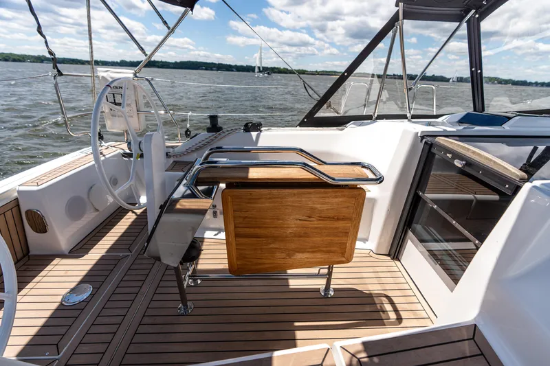 Slide: The Image of 2023 Hanse 348 yacht cockpit with wooden flooring and steering wheel on open water. - 28