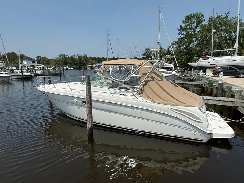 The Image of 2004 Sea Ray 290 Amberjack boat docked in a marina, featuring a beige canopy. - 1