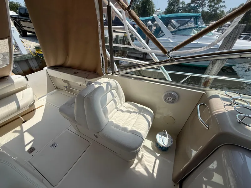 Slide: The Image of 2004 Sea Ray 290 Amberjack boat interior with white seating and docked boats in background. - 11