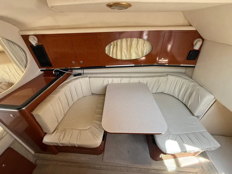 Slide: The Image of 2004 Sea Ray 290 Amberjack cabin with cushioned seating and table. - 20