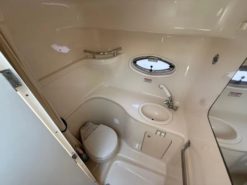 Slide: The Image of 2004 Sea Ray 290 Amberjack boat bathroom with toilet, sink, and porthole window. - 24