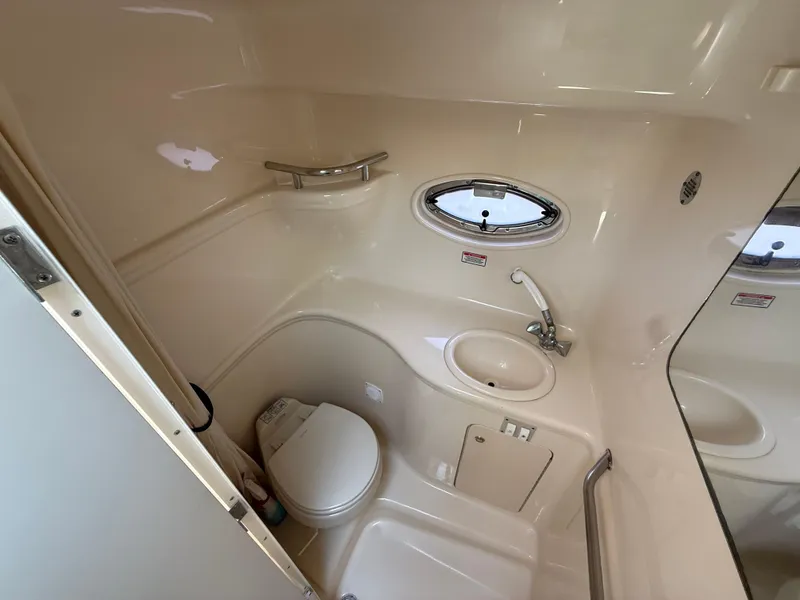 Slide: The Image of 2004 Sea Ray 290 Amberjack bathroom with toilet, sink, and porthole window. - 25