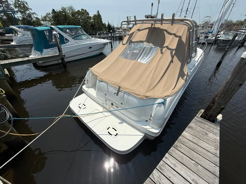 Slide: The Image of 2004 Sea Ray 290 Amberjack docked with tan cover, reflecting sunlight on water. - 6