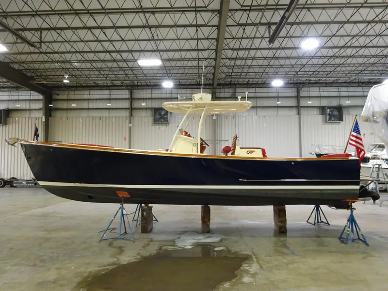 The Image of 2007 Hinckley T29C boat in a warehouse, elevated on stands, with an American flag. - 0