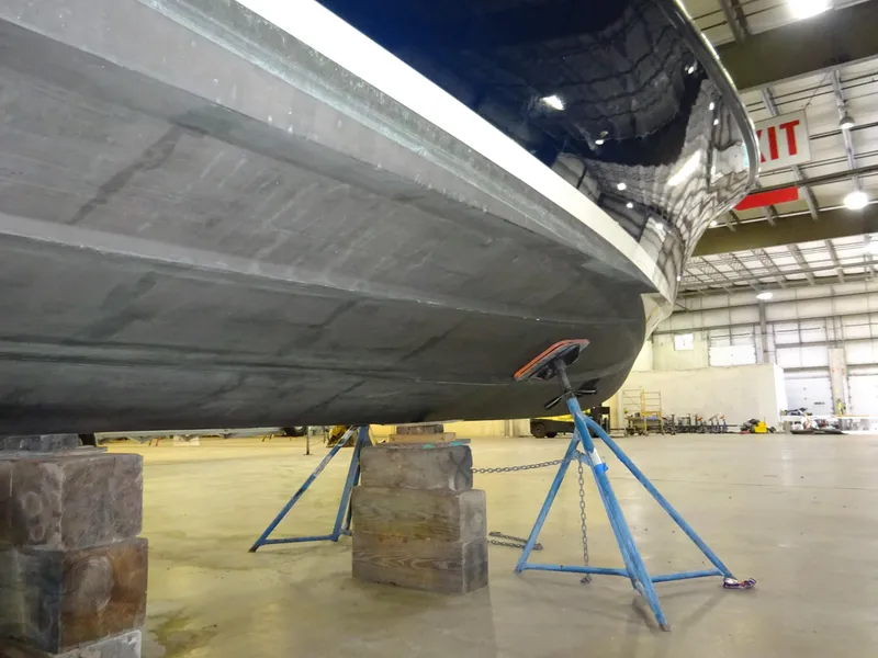 Slide: The Image of 2007 Hinckley T29C boat hull in a warehouse, supported by stands and blocks. - 43