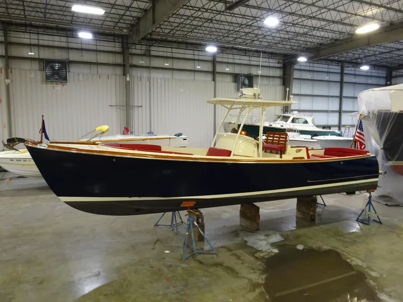 Slide: The Image of 2007 Hinckley T29C boat in indoor storage, featuring a sleek navy hull and red seating. - 6