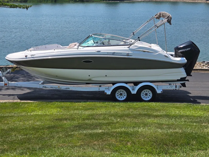 Slide: The Image of 2014 Hurricane SunDeck 2200 OB boat on trailer by a lake. - 0
