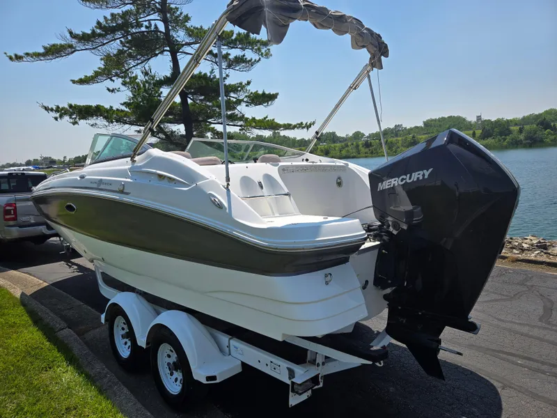 Slide: The Image of 2014 Hurricane SunDeck 2200 OB boat on trailer by a lake. - 1