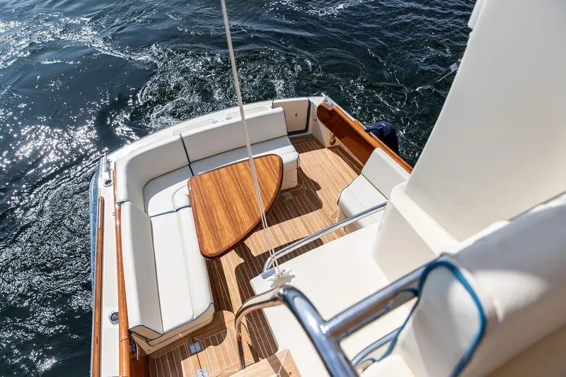 Slide: The Image of 2017 Hinckley Talaria 43 Flybridge with elegant seating and wooden table on deck. - 17