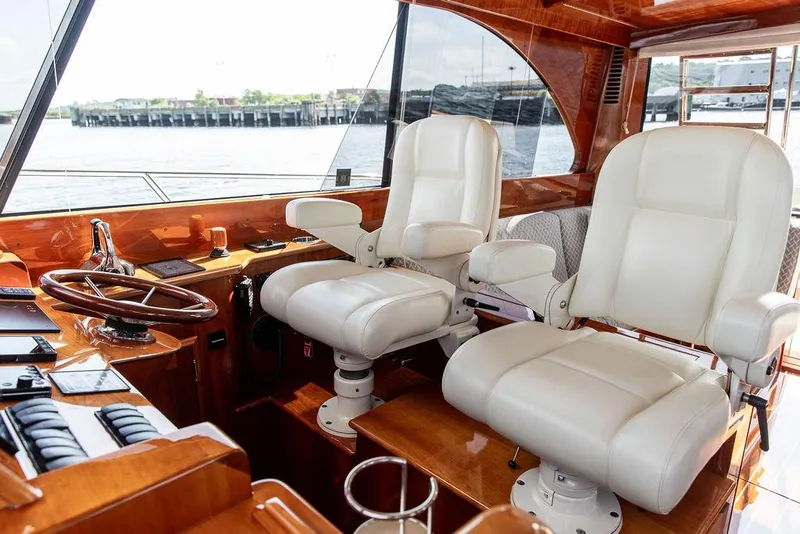 Slide: The Image of Interior of 2017 Hinckley Talaria 43 Flybridge with luxurious white captain chairs and wooden dashboard. - 23