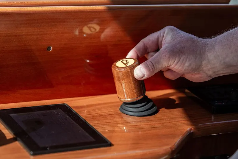 Slide: The Image of Hand operating joystick on 2017 Hinckley Talaria 43 Flybridge yacht's wooden dashboard. - 25