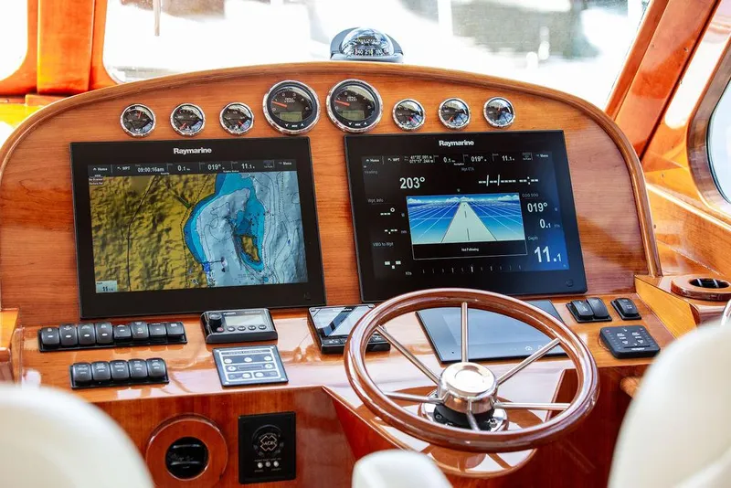 Slide: The Image of Hinckley Talaria 43 Flybridge 2017 helm with Raymarine navigation displays and wooden steering wheel. - 26