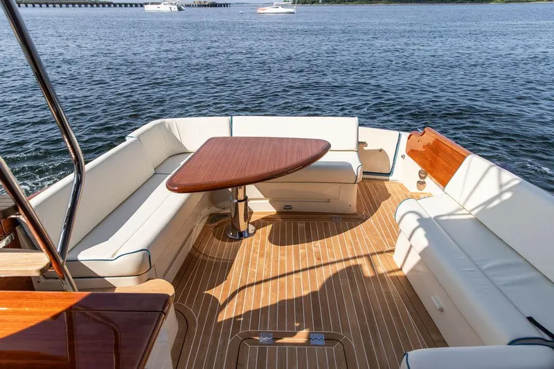 Slide: The Image of 2017 Hinckley Talaria 43 Flybridge yacht with elegant seating and wooden table on deck. - 5