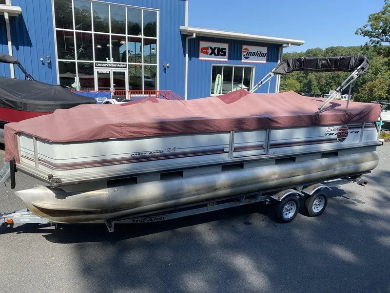 Slide: The Image of 1994 Sun Tracker Party Barge 24 pontoon boat with cover, parked on a trailer. - 8