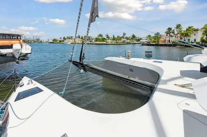 Slide: The Image of 2019 McConaghy MC60 catamaran on a sunny waterfront with palm trees and boats. - 13