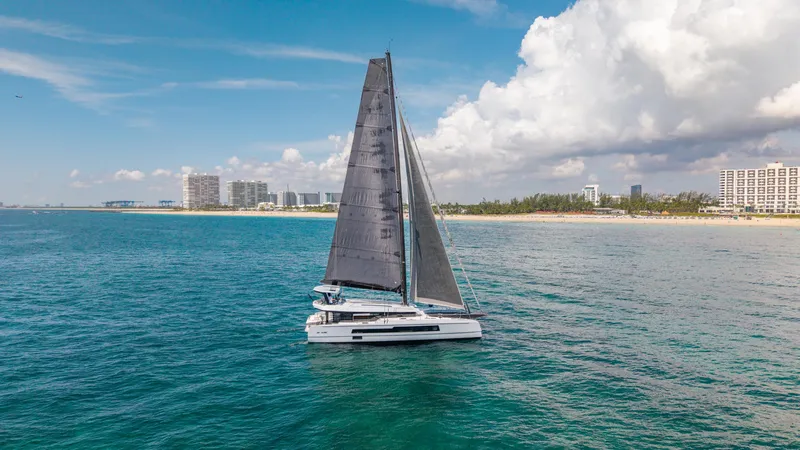 Slide: The Image of 2019 McConaghy MC60 sailing near a coastal city under a partly cloudy sky. - 4