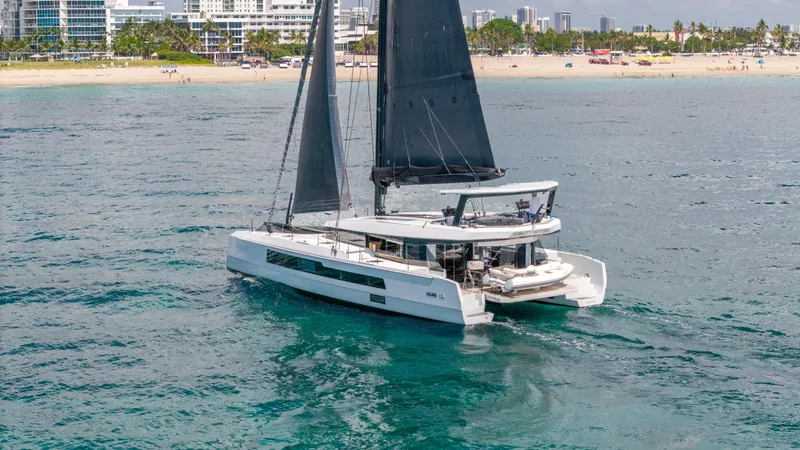 Slide: The Image of 2019 McConaghy MC60 catamaran sailing near a beach with city skyline backdrop. - 7