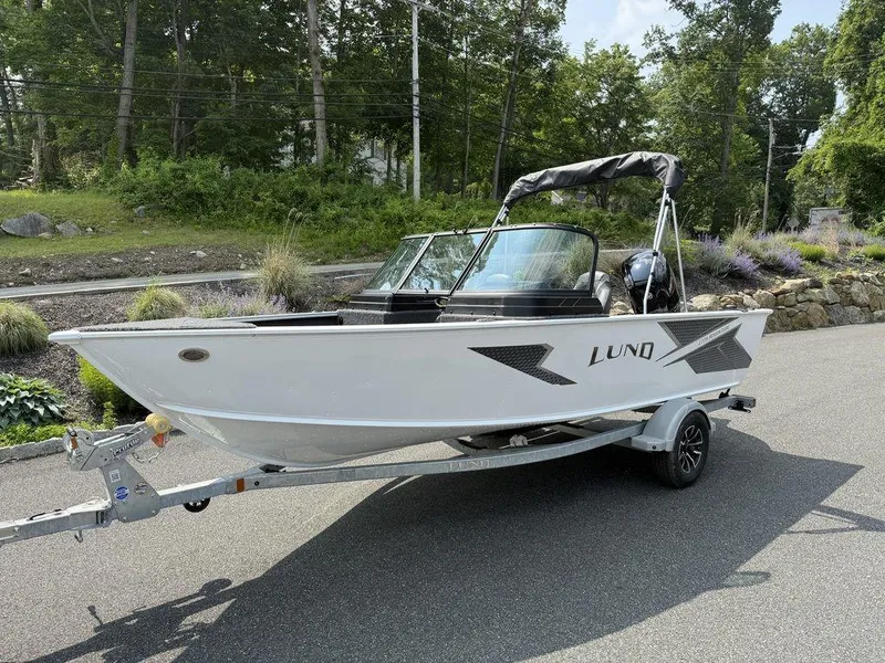 Slide: The Image of 2025 Lund 1775 Adventure Sport boat on trailer, parked on a road with greenery. - 15