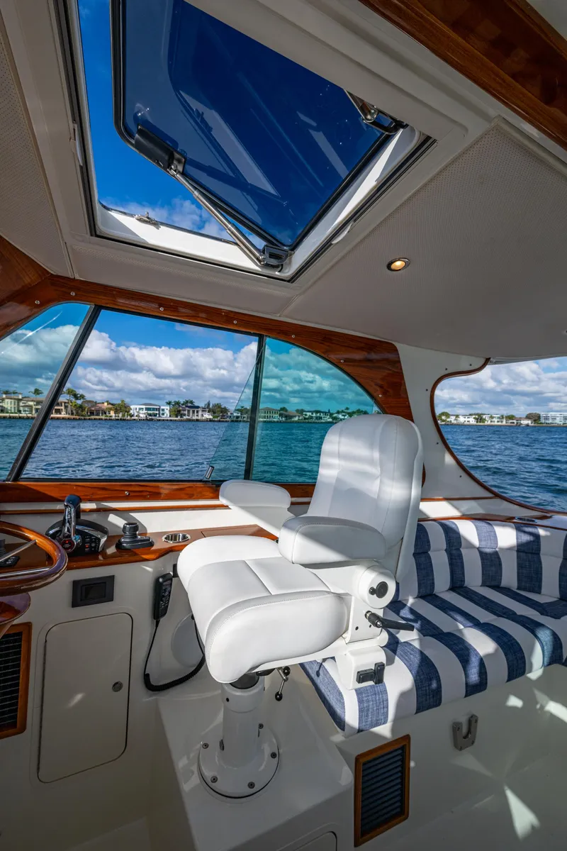 Slide: The Image of 2024 Hinckley 35 boat interior with captain's chair, striped seating, and open sunroof. - 15