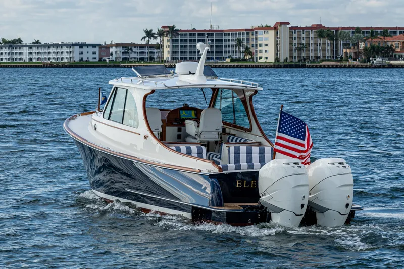 Slide: The Image of 2024 Hinckley 35 boat cruising on water, American flag, coastal buildings in background. - 3