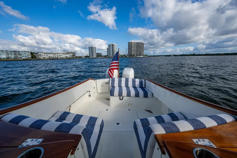 Slide: The Image of Hinckley 35 boat, 2024 model, with striped seating, cruising near coastal buildings under a cloudy sky. - 6