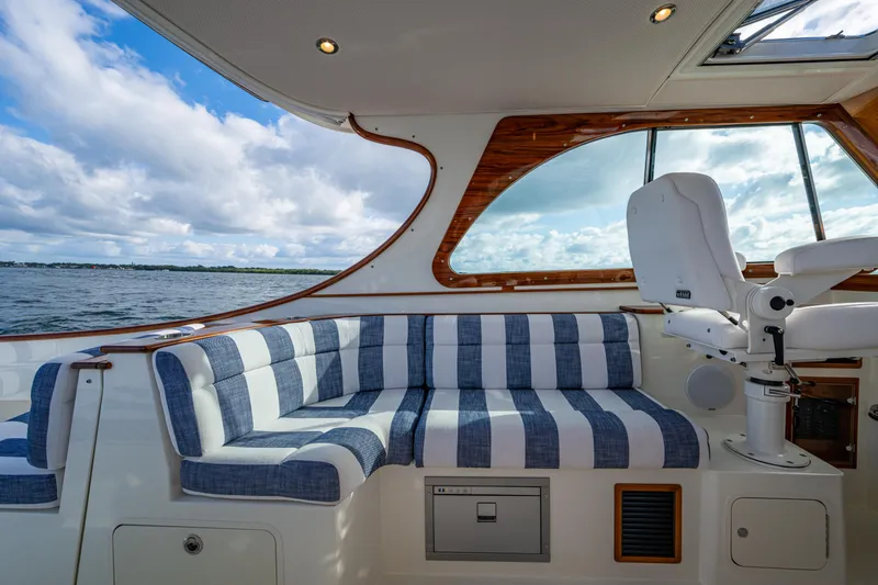 Slide: The Image of 2024 Hinckley 35 yacht interior with striped seating, wooden accents, and ocean view. - 11