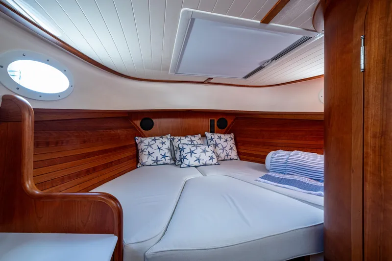 Slide: The Image of 2024 Hinckley 35 yacht interior with cozy wooden cabin and star-patterned pillows. - 18