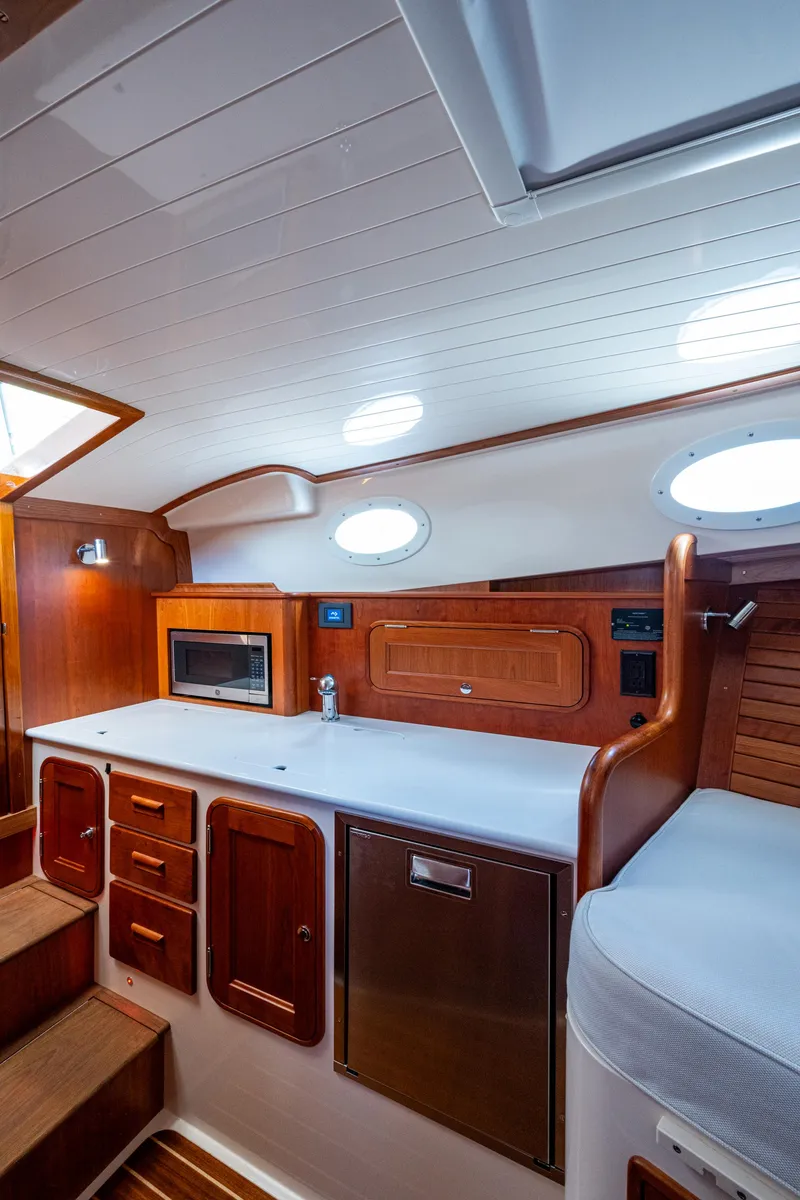 Slide: The Image of 2024 Hinckley 35 yacht interior with wooden cabinetry and modern kitchen amenities. - 19