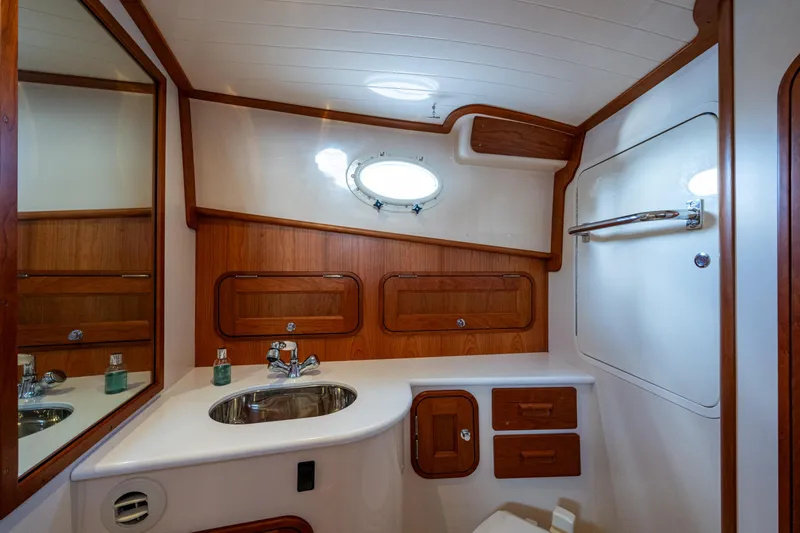 Slide: The Image of 2024 Hinckley 35 yacht bathroom with wooden accents, stainless steel sink, and porthole window. - 21