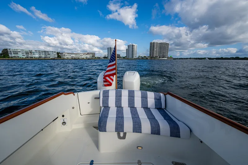 Slide: The Image of 2024 Hinckley 35 boat with striped seating, American flag, and waterfront cityscape. - 7
