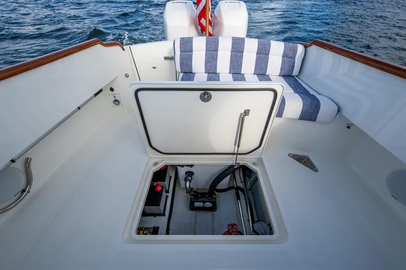 Slide: The Image of 2024 Hinckley 35 boat deck with open hatch, striped seating, and ocean backdrop. - 8