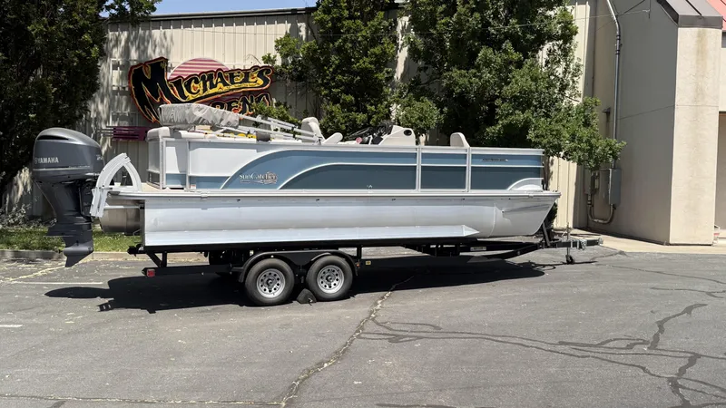 The Image of 2023 SunCatcher Select 322FC pontoon boat on trailer, parked near a building. - 0