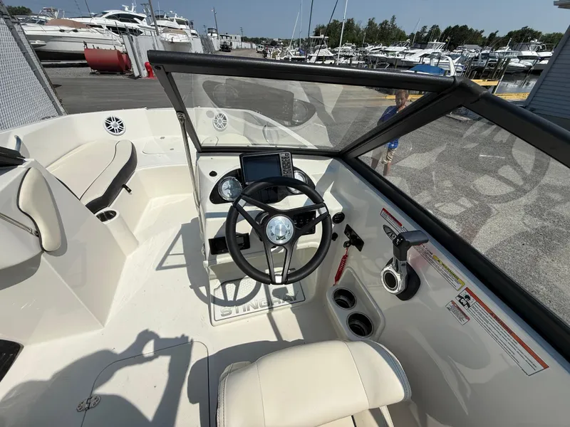 Slide: The Image of 2023 Stingray 191 DC boat interior with steering wheel and dashboard, docked at marina. - 13