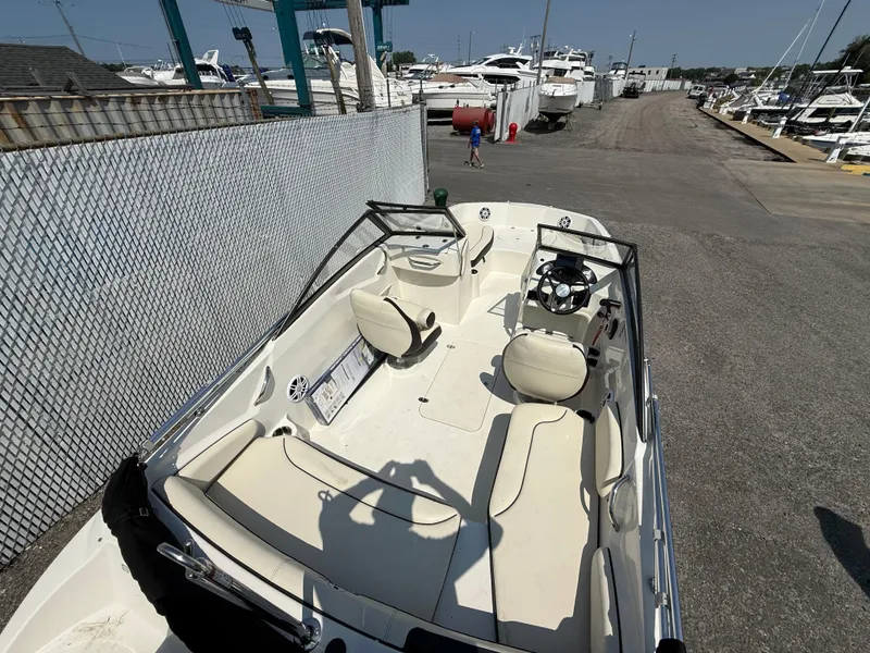 Slide: The Image of 2023 Stingray 191 DC boat with beige seating, docked near other boats. - 16