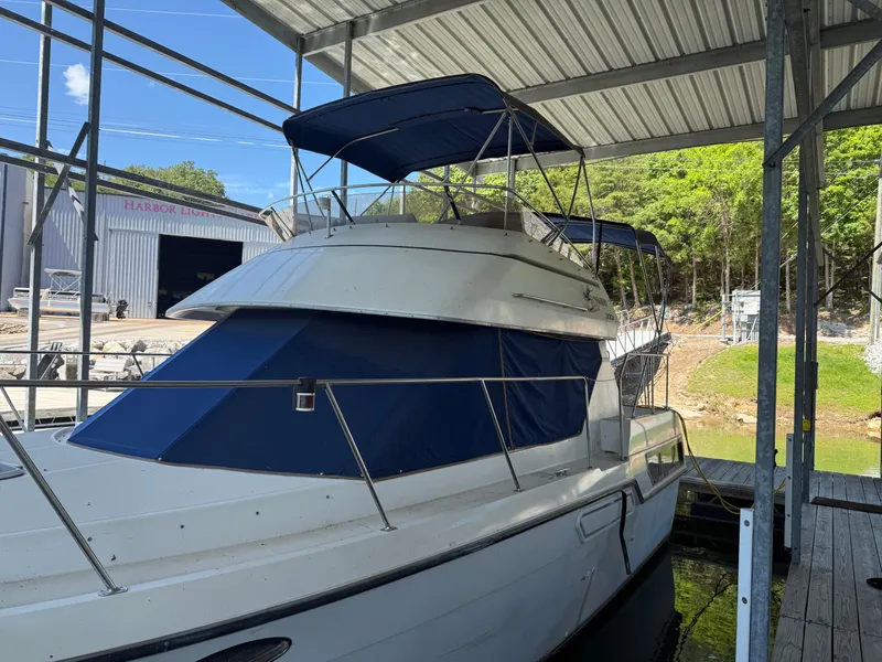 Slide: The Image of 1994 Carver 300 yacht docked under a metal canopy with blue canvas covers. - 1