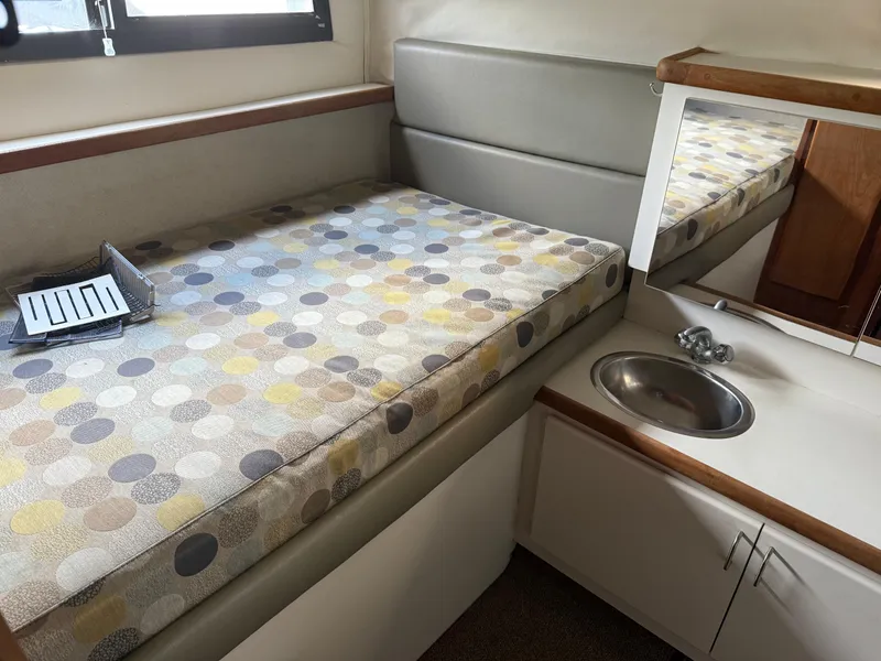 Slide: The Image of 1994 Carver 300 cabin interior with patterned bed, sink, and mirror. - 11