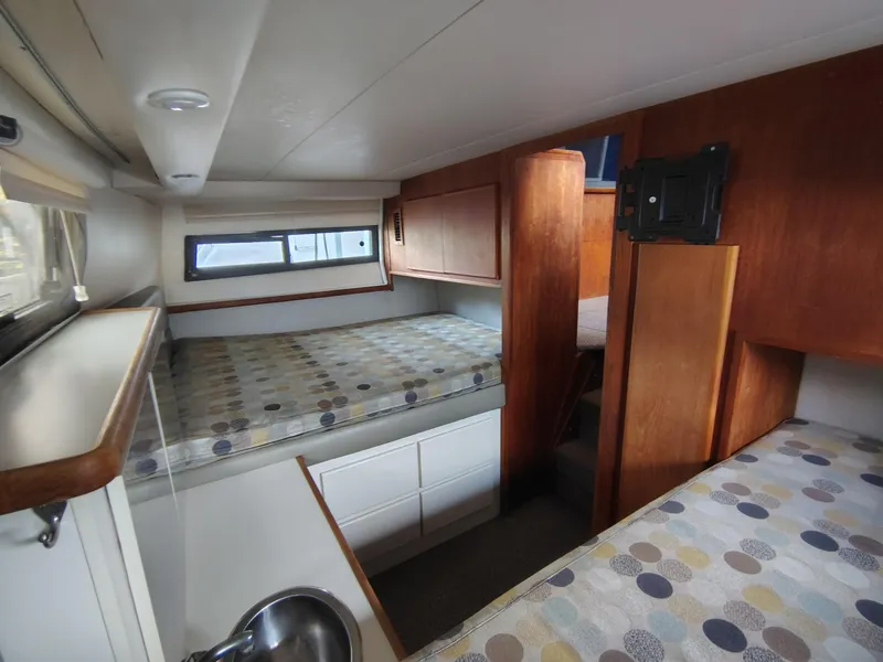 Slide: The Image of 1994 Carver 300 boat interior with twin beds and wooden cabinetry. - 13