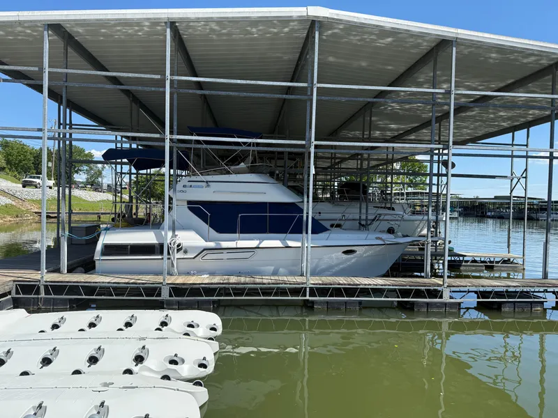 Slide: The Image of 1994 Carver 300 boat docked under a covered marina on a sunny day. - 7