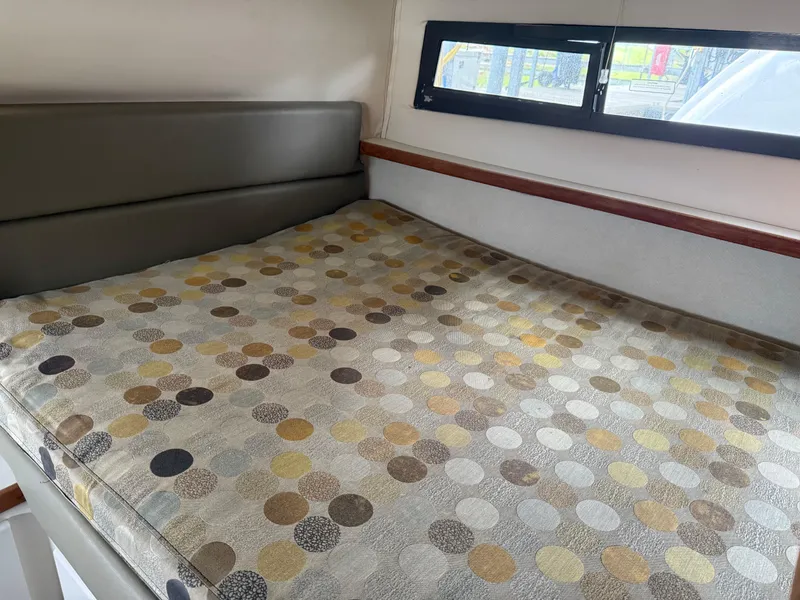 Slide: The Image of 1994 Carver 300 boat interior with patterned bed and window view. - 12