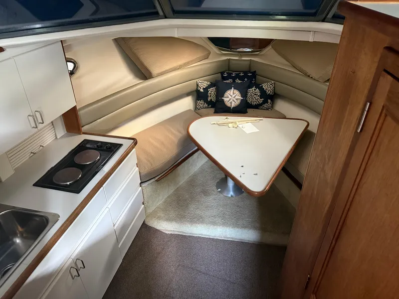 Slide: The Image of 1994 Carver 300 boat interior with kitchenette, dining area, and cozy seating. - 23