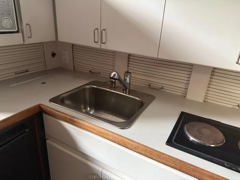 Slide: The Image of 1994 Carver 300 kitchen area with sink, stove, and white cabinetry. - 27
