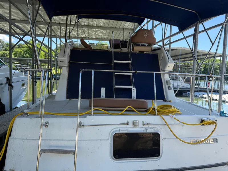 Slide: The Image of 1994 Carver 300 boat docked under a covered marina with blue canopy and yellow cords. - 4